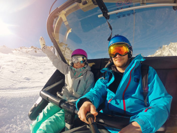 winter holidays - happy couple taking selfie in chairlift at ski resort